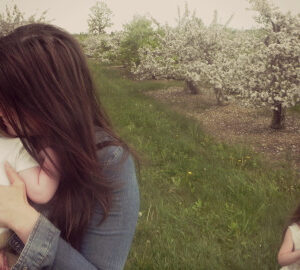 mother in blossoming orchard with children