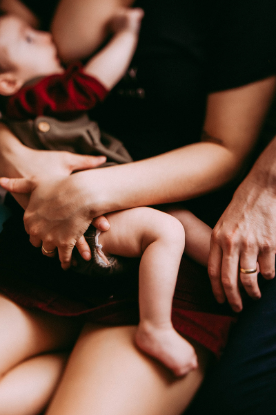 mother breastfeeding baby with father's  embrace